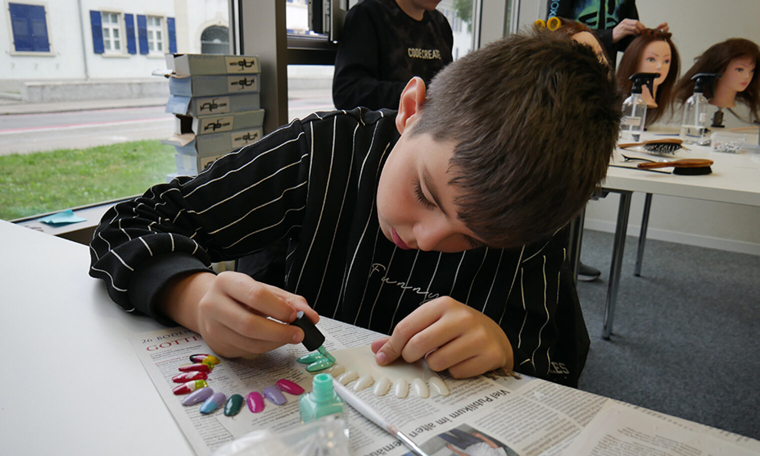 Schüler lackiert Kunststoff-Fingernägel im Rahmen der Berufsorientierung (Kosmetiker) an der Bildungsakademie Singen.