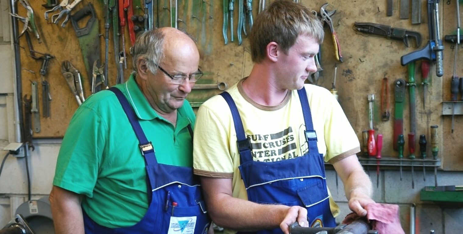 Ein junger und alter Mann arbeiten zusammen in einer Werkstatt