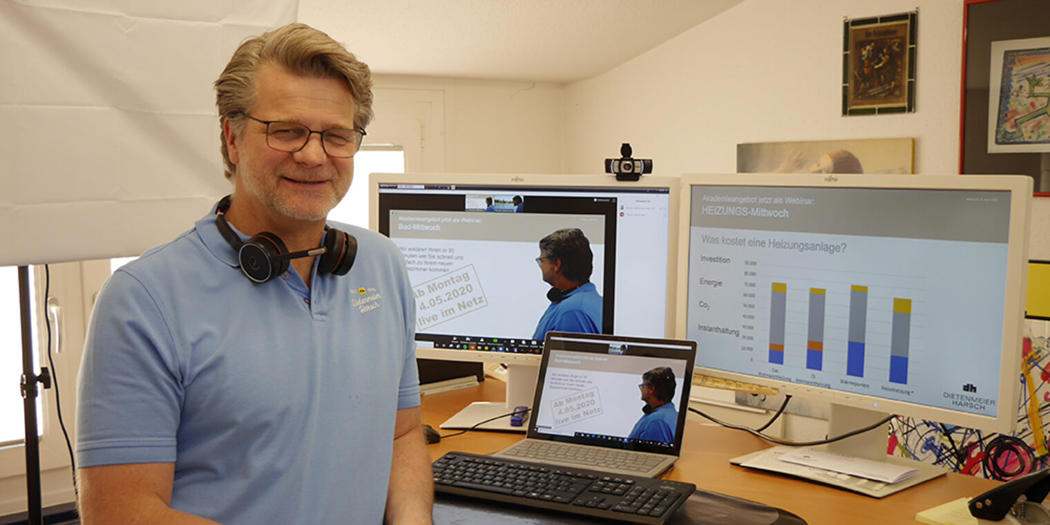 Thomas Dietenmeier mit Headset vor drei Bildschirmen.