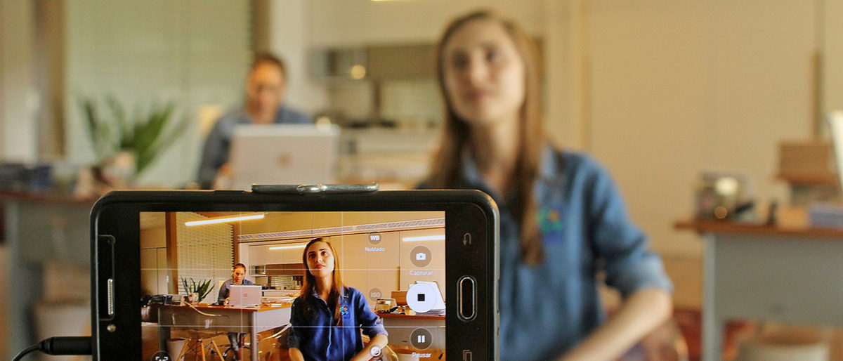 Statt Jobmesse oder Schulbesuch: Jetzt neue Azubis finden mit einem selbst gedrehten Recruiting-Video! Smartphone filmt Mann und Frau im Büro.