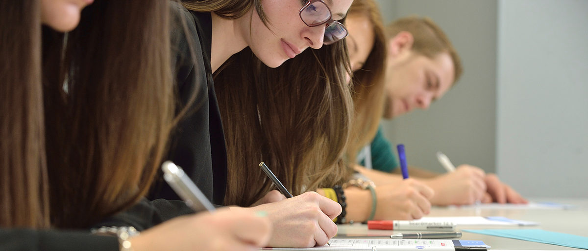 Prüfungen im Handwerk Konzentrierte, von Hand schreibende Schüler.