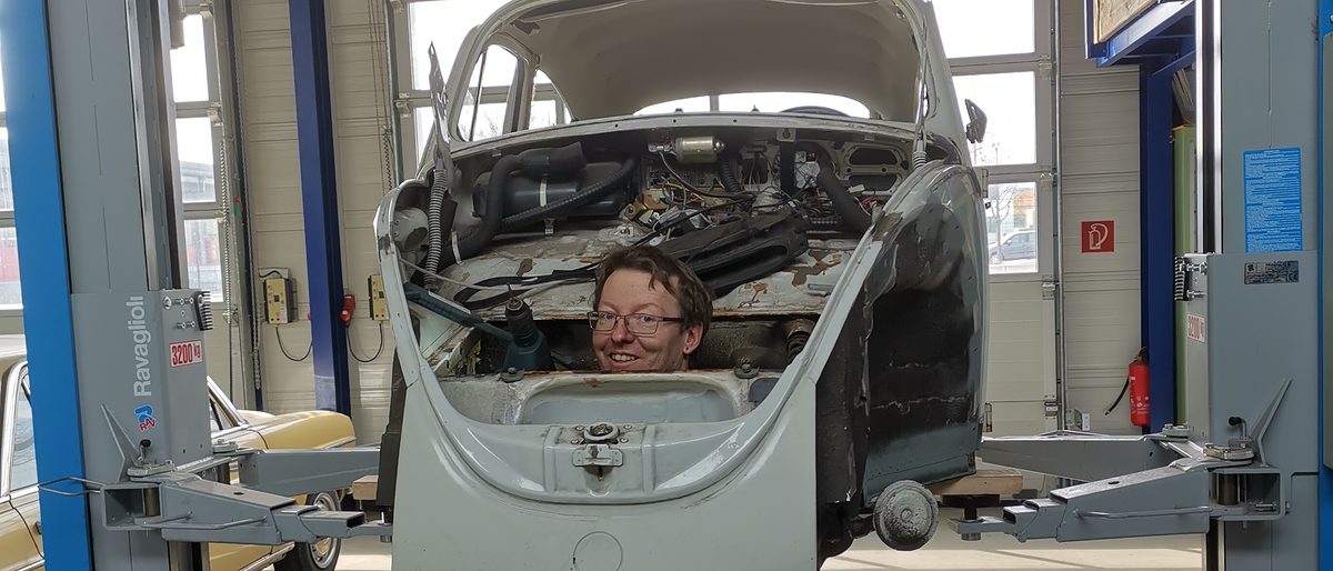 Rückenwind dank Meistergründungsprämie Stefan Werne schaut durch Oldtimer-Karosserie in die Kamera.