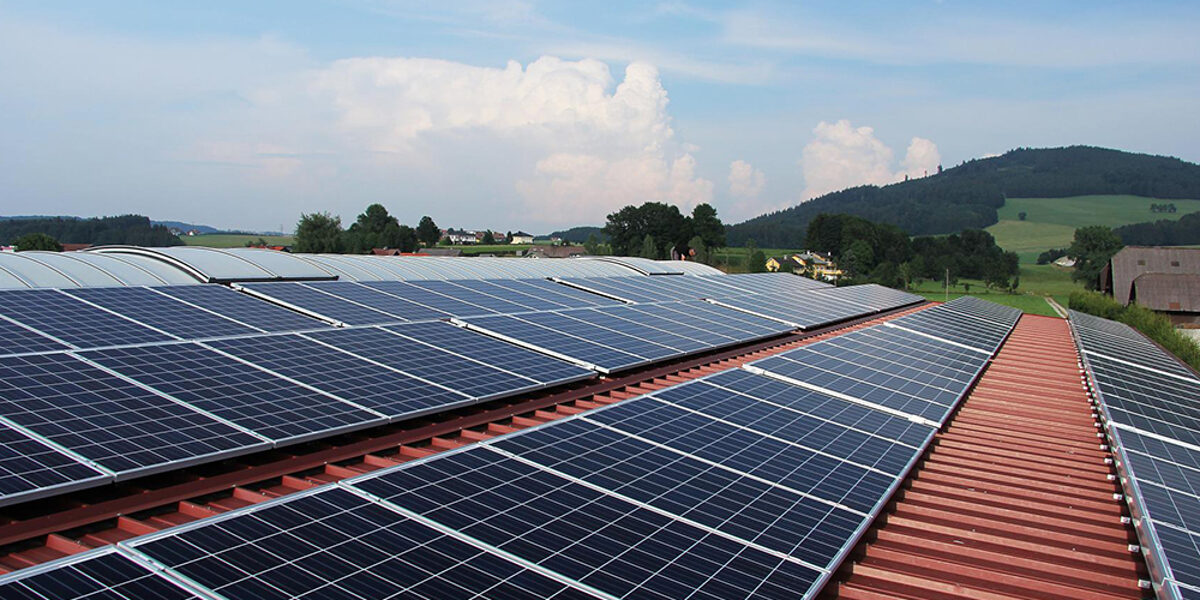 Solarpaneele auf Dachziegeln, im Hintergrund grüner Hügel.