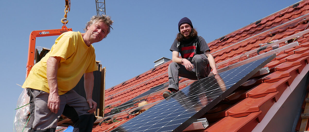 Michael Simon (links), Geschäftsführer von Sunny Solartechnik, bringt mit seinem Mitarbeiter Johannes Stiefel ein Solarmodul auf einem Dach in Hegne an. 