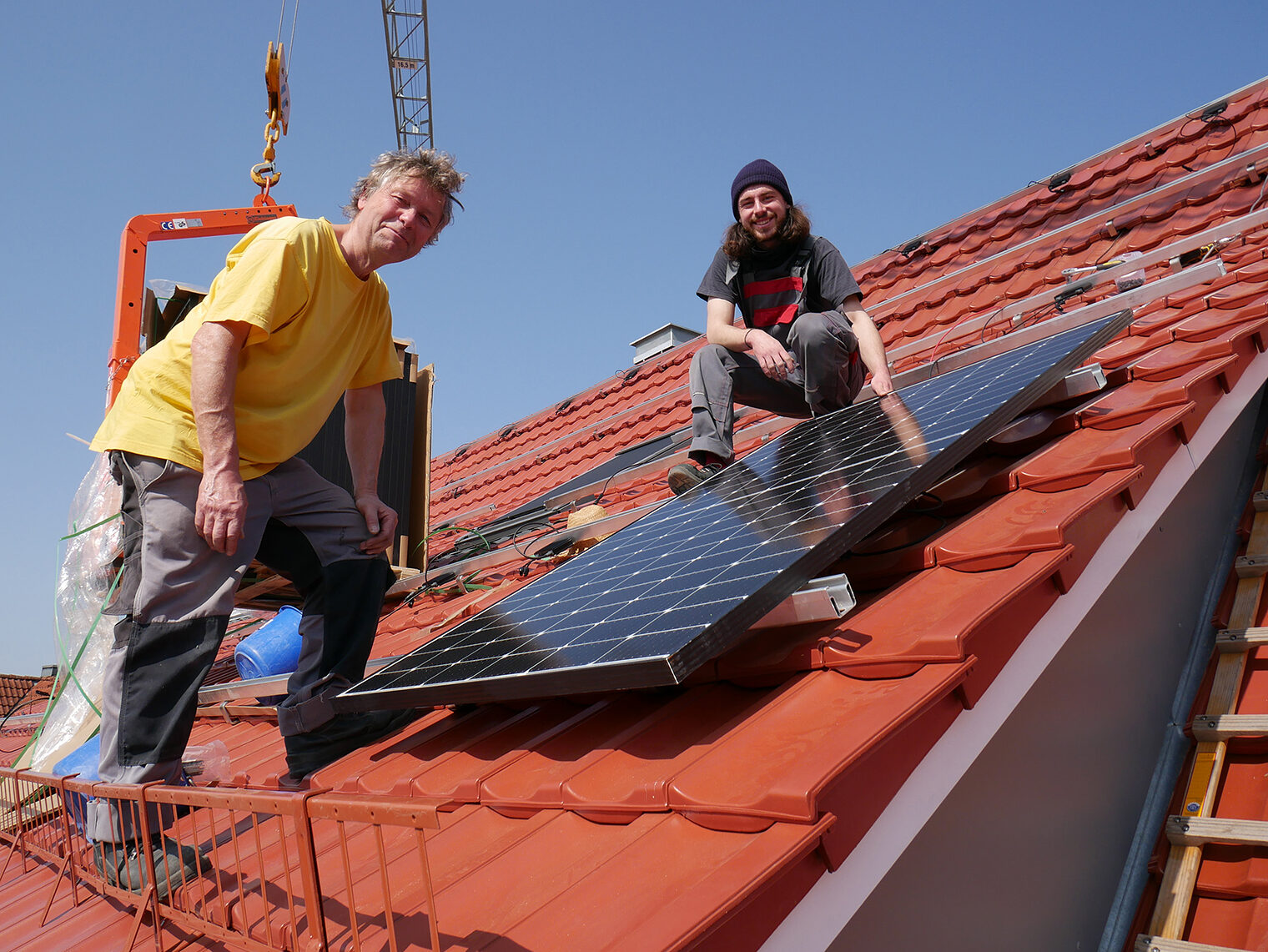 Michael Simon (links), Geschäftsführer von Sunny Solartechnik, bringt mit seinem Mitarbeiter Johannes Stiefel ein Solarmodul auf einem Dach in Hegne an. 
