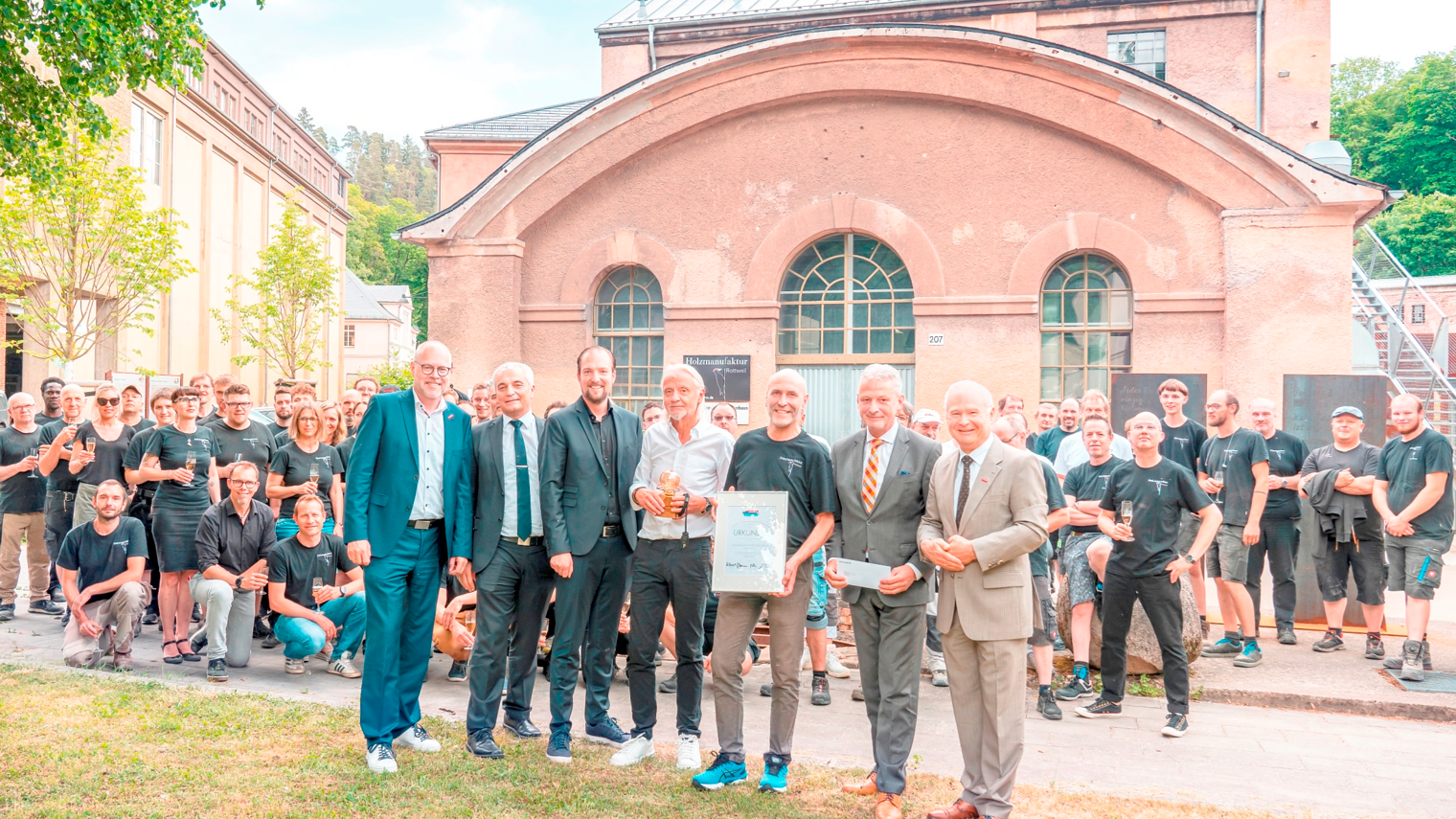 Team Holzmanufaktur Rottweil steht vor einem alten Gebäude.