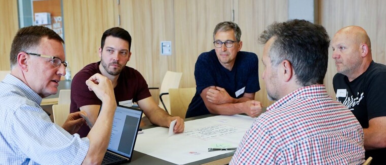 New Work-Studie 5 Männer sitzen in einer Besprechungsrunde an einem Tisch