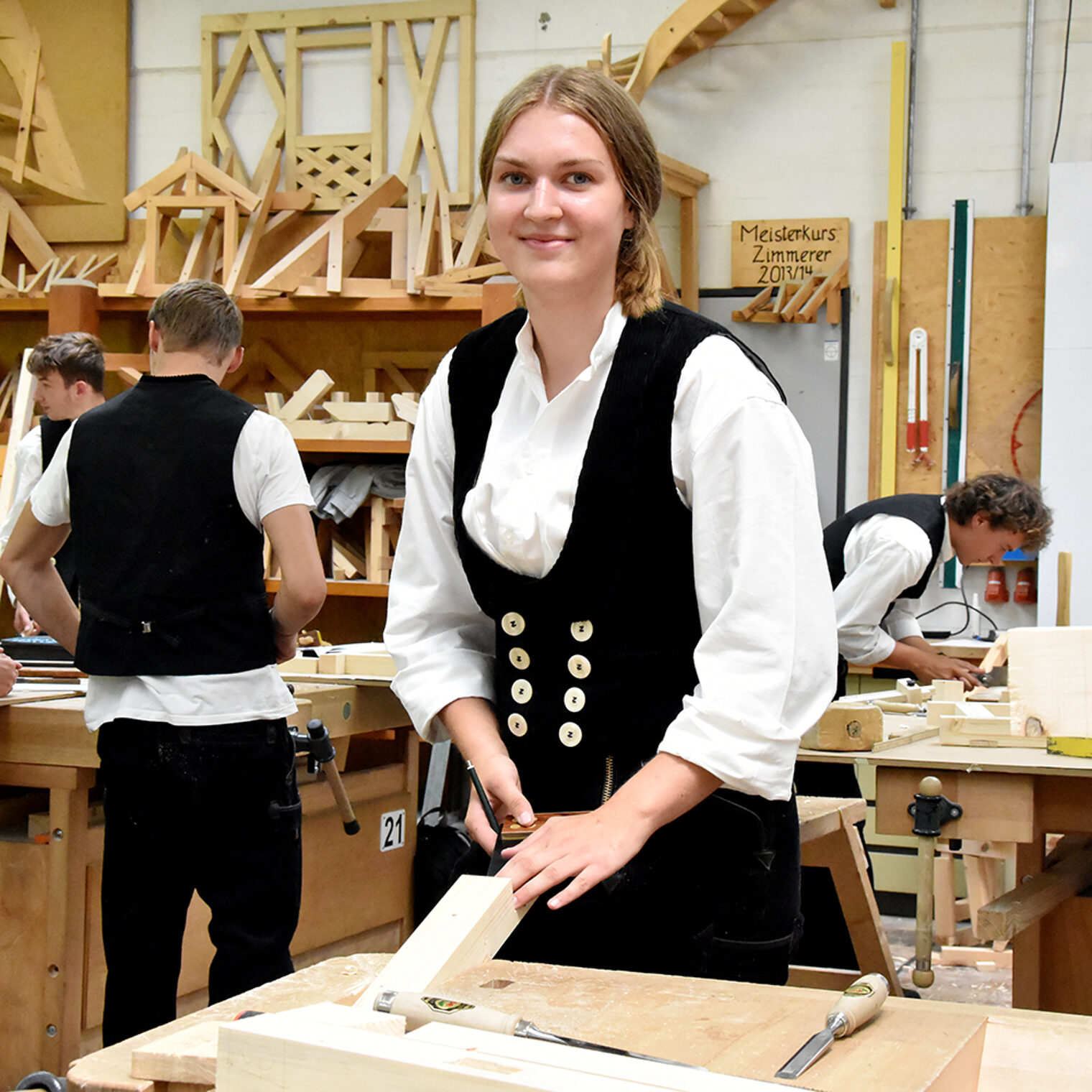 Junge Zimmererin in typischer Kluft an einer Werkbank in der Bildungsakademie Rottweil.