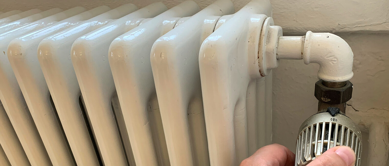 Heizkörper mit Hand am Thermostatknopf