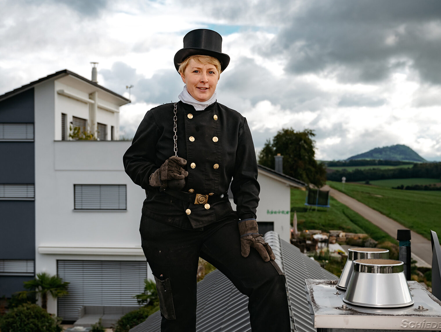 Schornsteinfegermeisterin Simone Zeller in ihrer Kluft auf einem Dach.