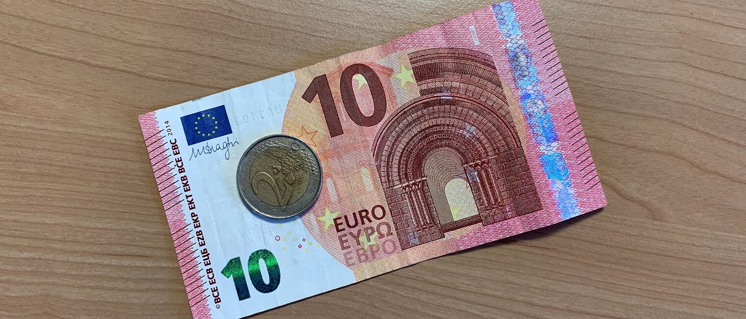 10-Euro-Schein mit 2-Euro-Stück auf Schreibtisch