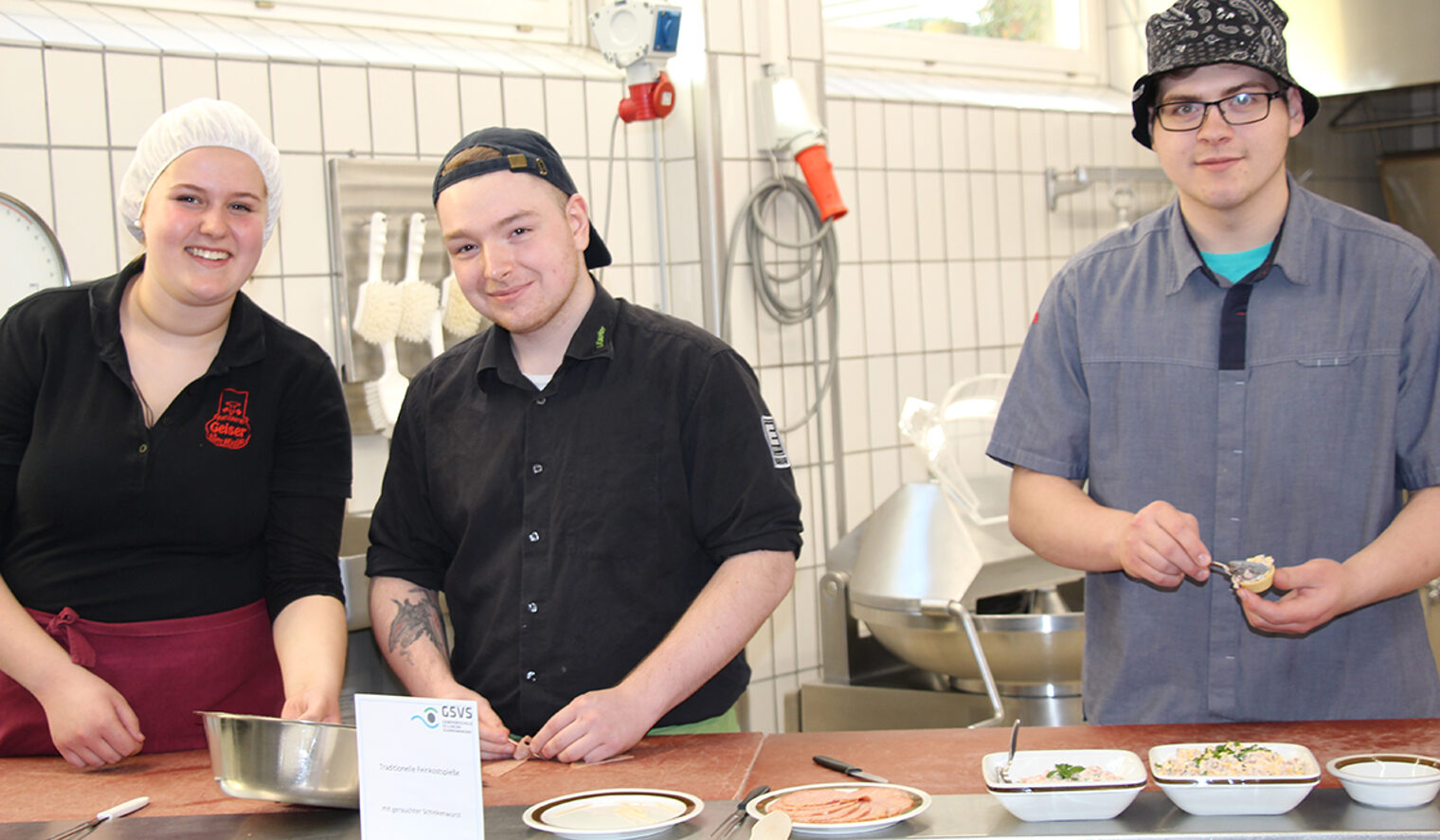 Eine Schülerin und zwei Schüler der Gewerbeschule Schwenningen beim Anrichten von Fleischpastetchen.