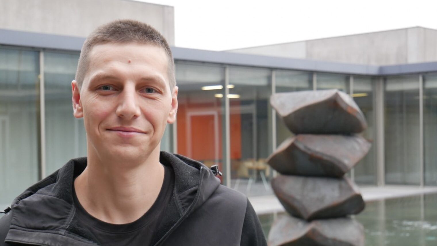 Mann vor modernem Gebäude und Skulptur