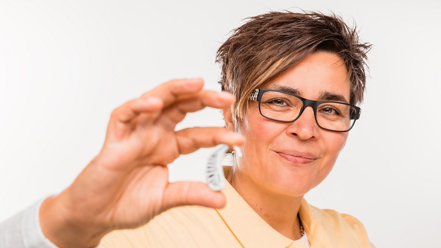 Frau hält Hörgerät in der Hand