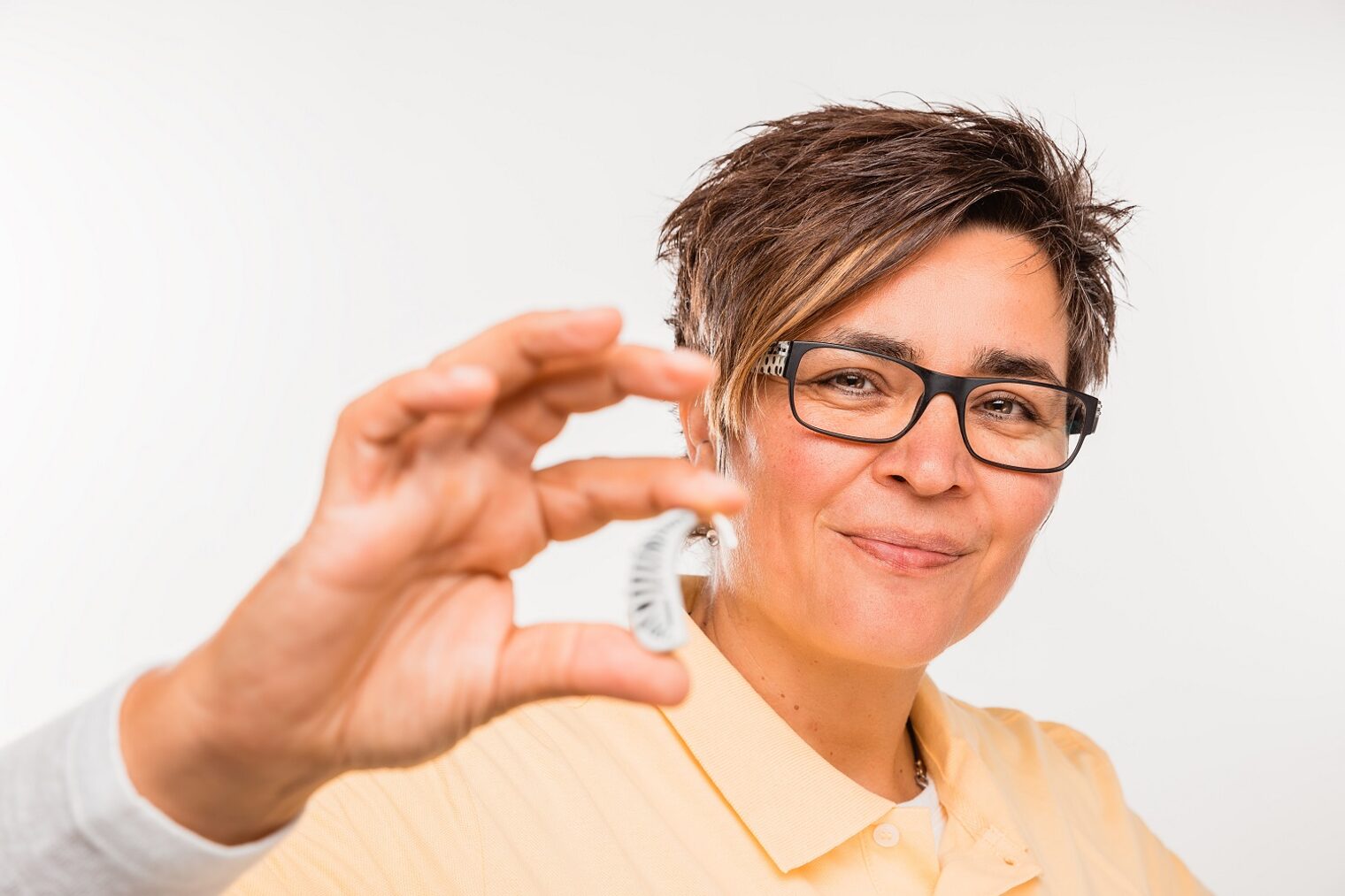 Frau hält Hörgerät in der Hand