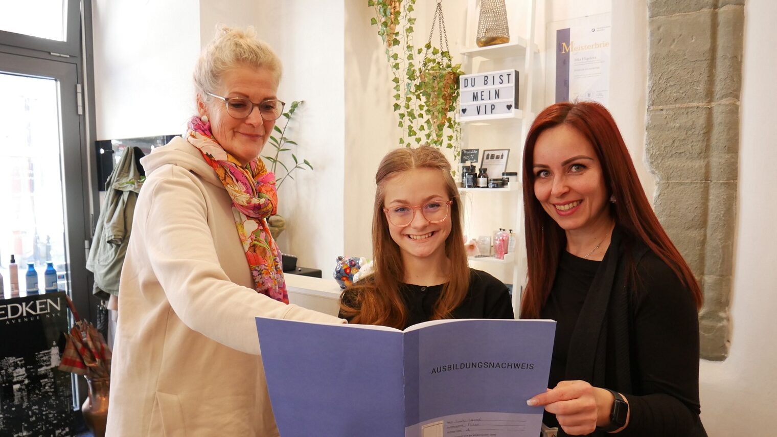 Zwei Frauen und ein Mädchen (mit Berichtsheft in der Hand)