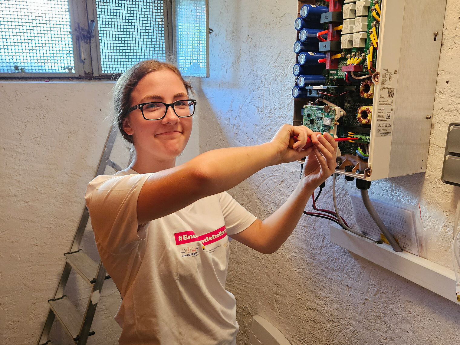 Energiewendehelferin Rosalie Rieger bei der Arbeit am Stromkasten in einem Keller.
