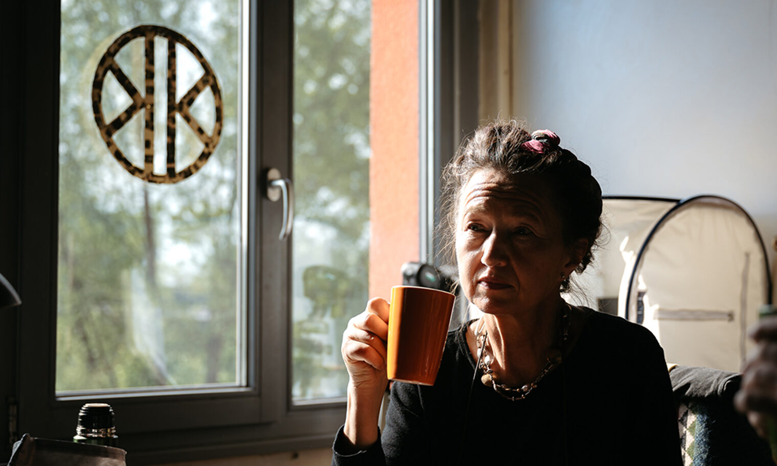 Goldschmiedemeisterin Karin Demmler sitzt mit Kaffeetasse in der Hand in ihrer Werkstatt.