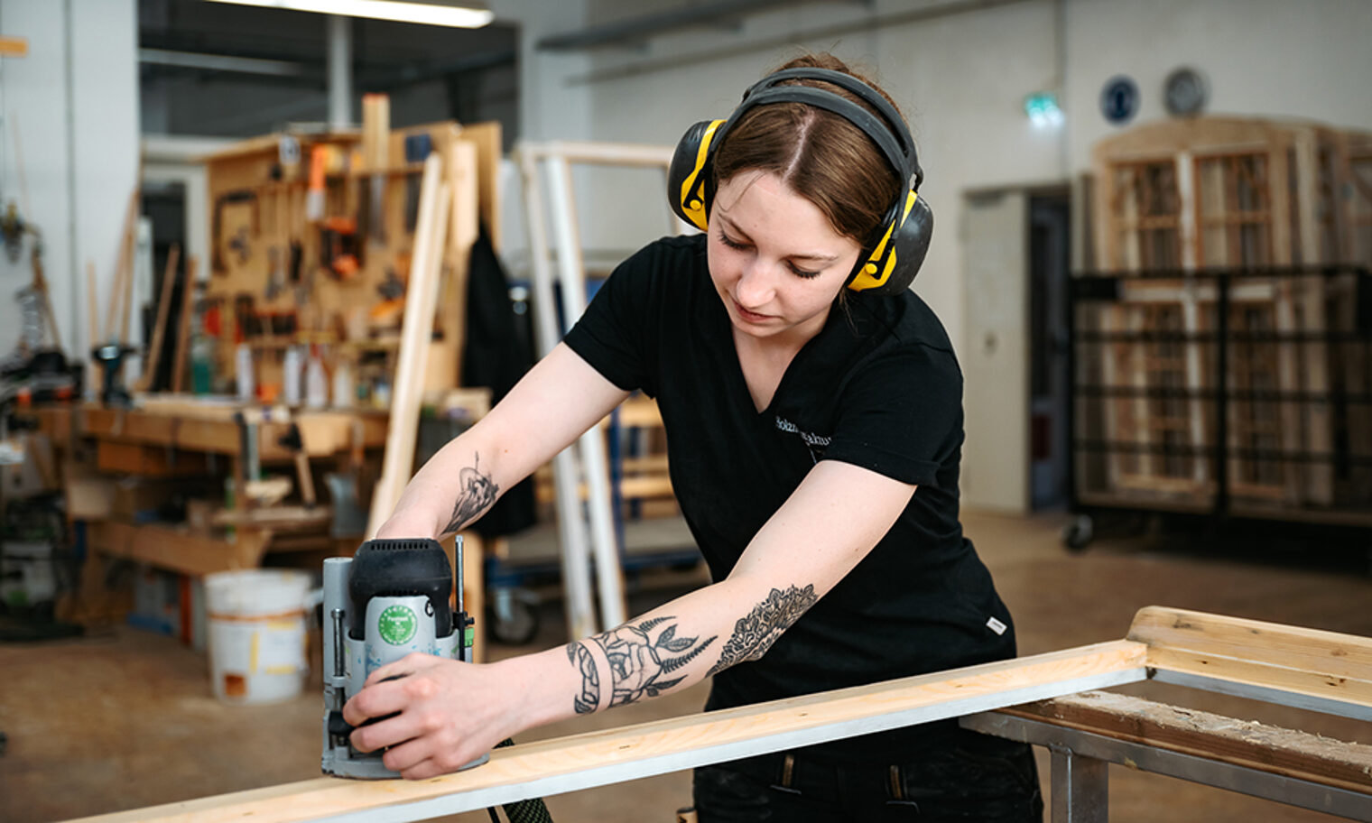Junge Mitarbeiterin mit Gehörschutz schleift Holz in der Holzmanufaktur Rottweil.