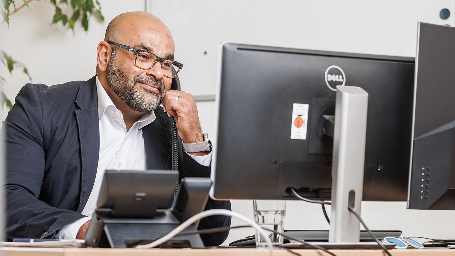 Der Kümmerer der Handwerkskammer Konstanz, Baris Abak, sitzt mit Telefonhörer am Ohr am Schreibtisch.