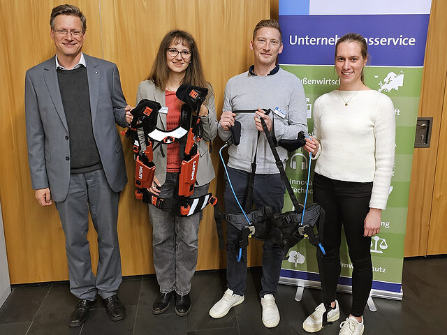 Gruppenfoto mit den Veranstaltern und zwei Exoskeletten, die Handwerker in der BA Singen testen konnten.