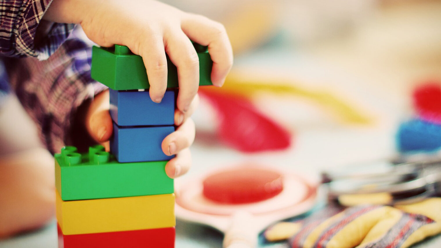 Kinderhände bauen Turm aus Bauklötzen