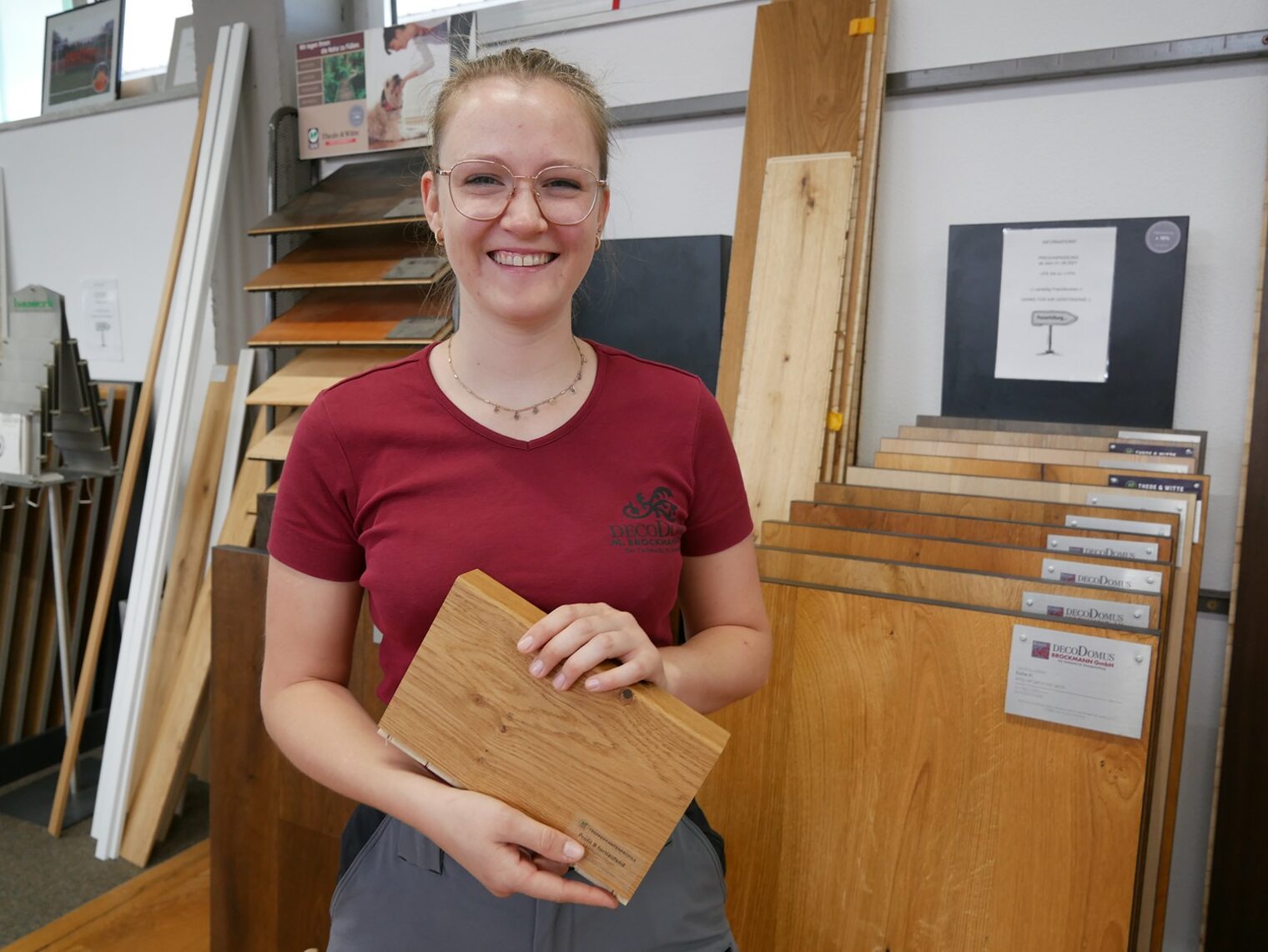 Junge Frau hält ein Stück Holz eines Bodenbelages in den Händen