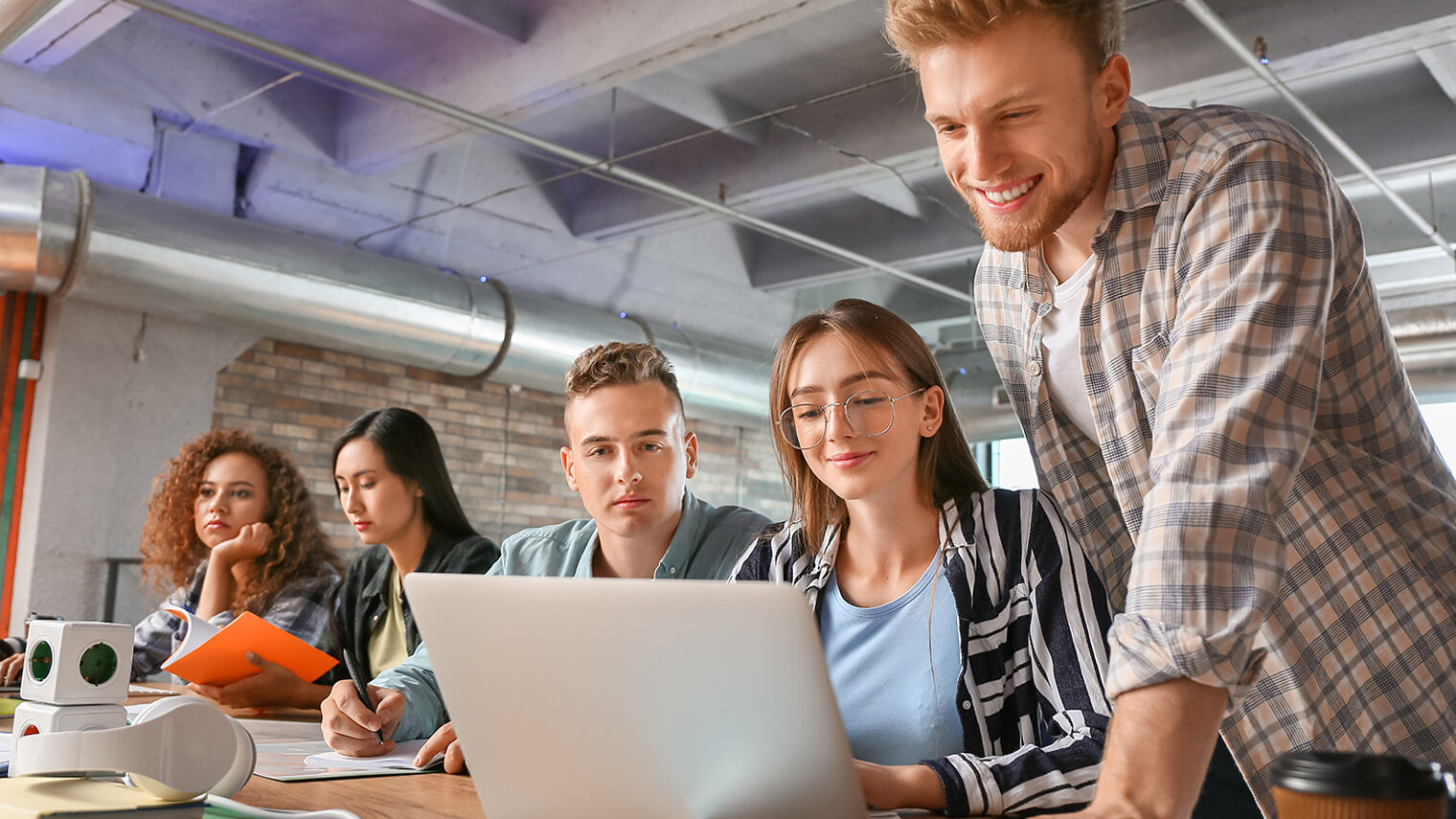 Junge, gut gelaunte Menschen vor Laptop