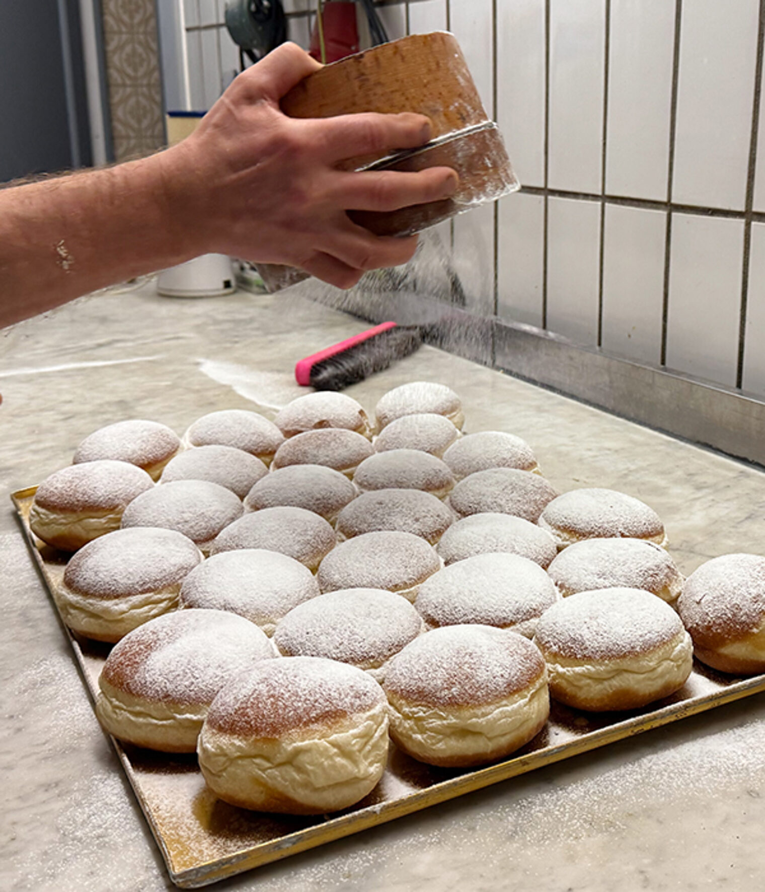 Berliner werden von Hand mit Puderzucker bestäubt.