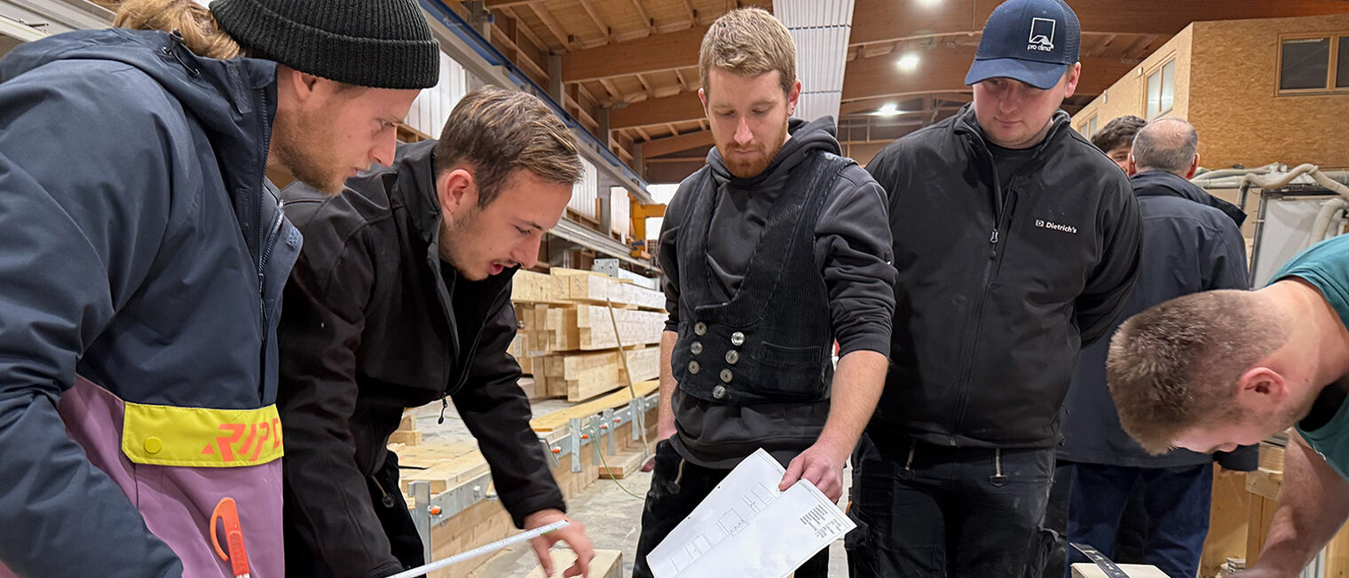 Studenten und Handwerksmeisterschüler arbeiten gemeinsam an der Konstruktion eines Fachwerkknotens.