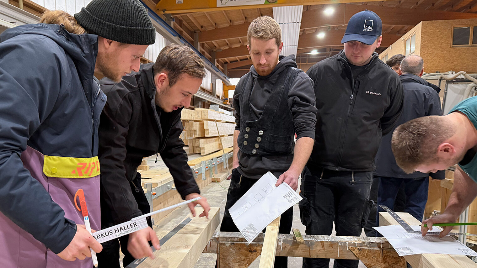 Studenten und Handwerksmeisterschüler arbeiten gemeinsam an der Konstruktion eines Fachwerkknotens.