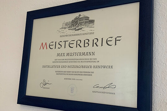 Gerahmter traditioneller Meisterbrief der Handwerkskammer Konstanz an einer weißen Wand.