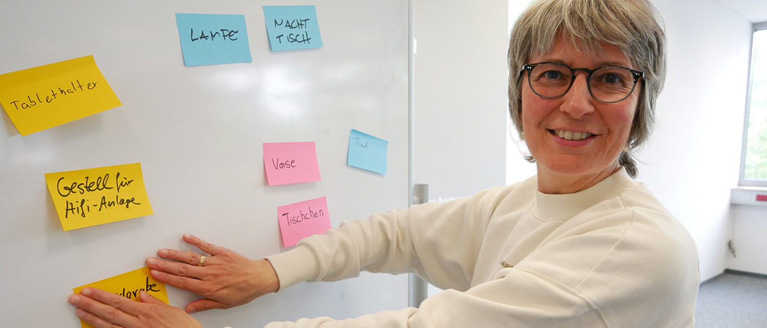 Dr. Maria klebt bunte Haftnotizen auf eine Tafel.