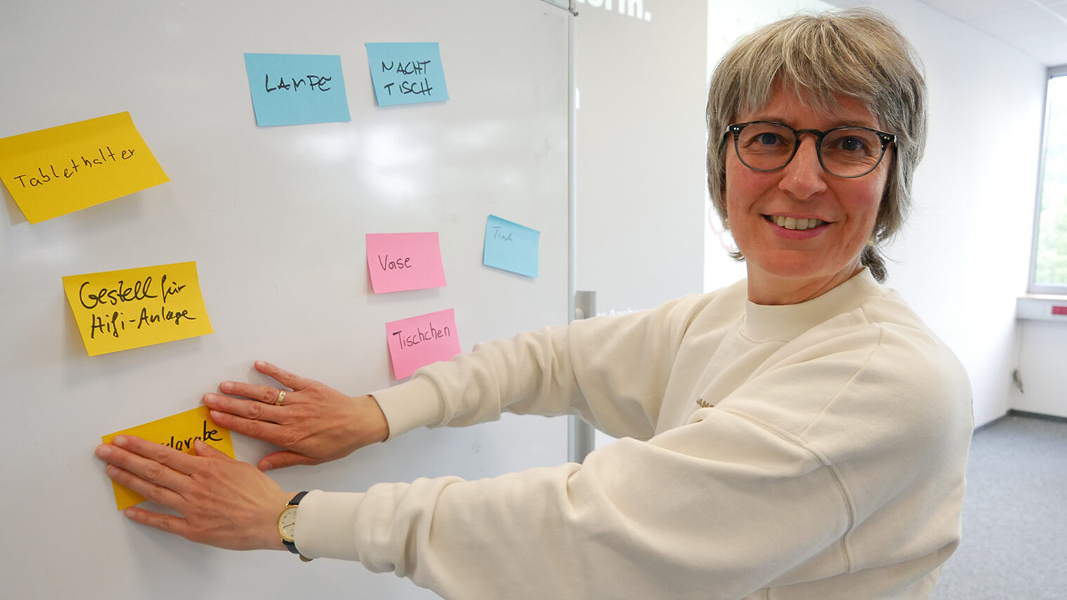 Dr. Maria klebt bunte Haftnotizen auf eine Tafel.
