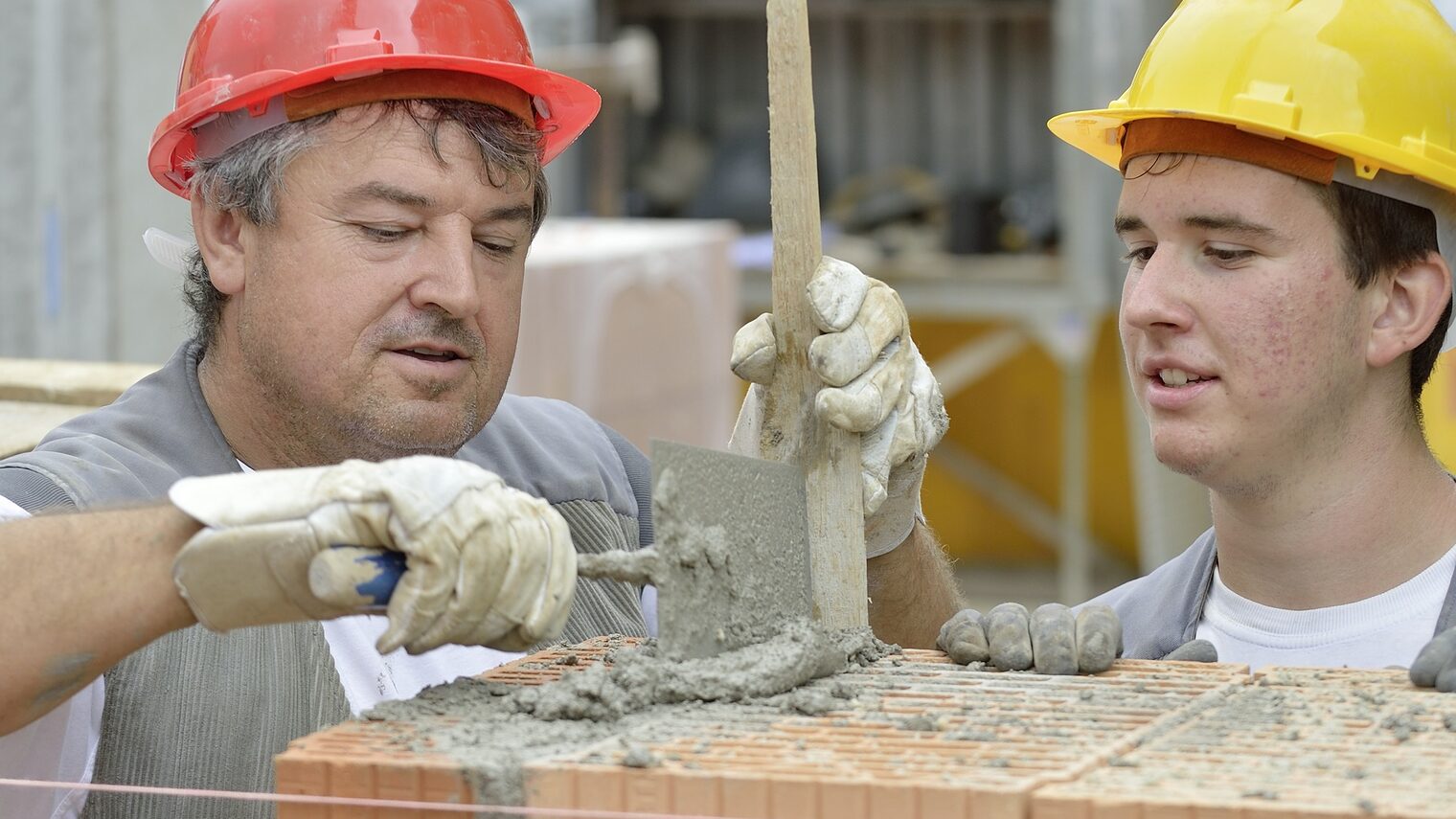 Maurer auf Baustelle mit Azubi