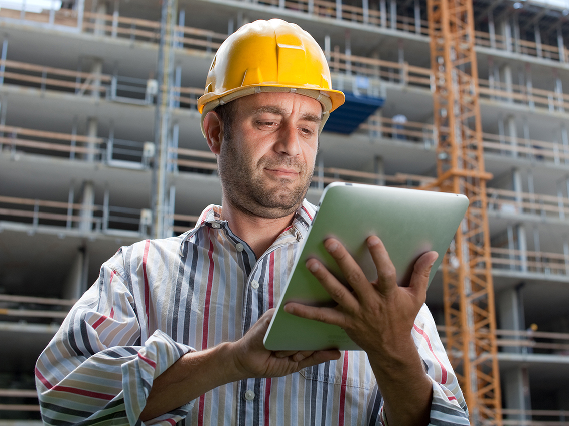 Bauarbeiter mit Tablet in der Hand auf einer Baustelle