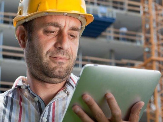 Bauarbeiter mit Tablet in der Hand auf einer Baustelle
