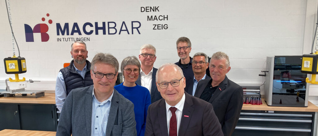 Präsident und Hauptgeschäftsführer durchschneiden rotes Band im Kreativraum in Tuttlingen. Im Hintergrund weitere Personen siehe Bildunterschrift.