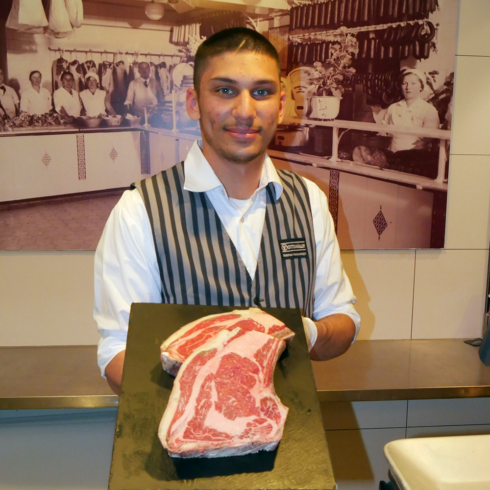 Metehan Kocaustaoglu, angehender Fleischerei-Fachverkäufer, präsentiert ein großes Stück Fleisch.