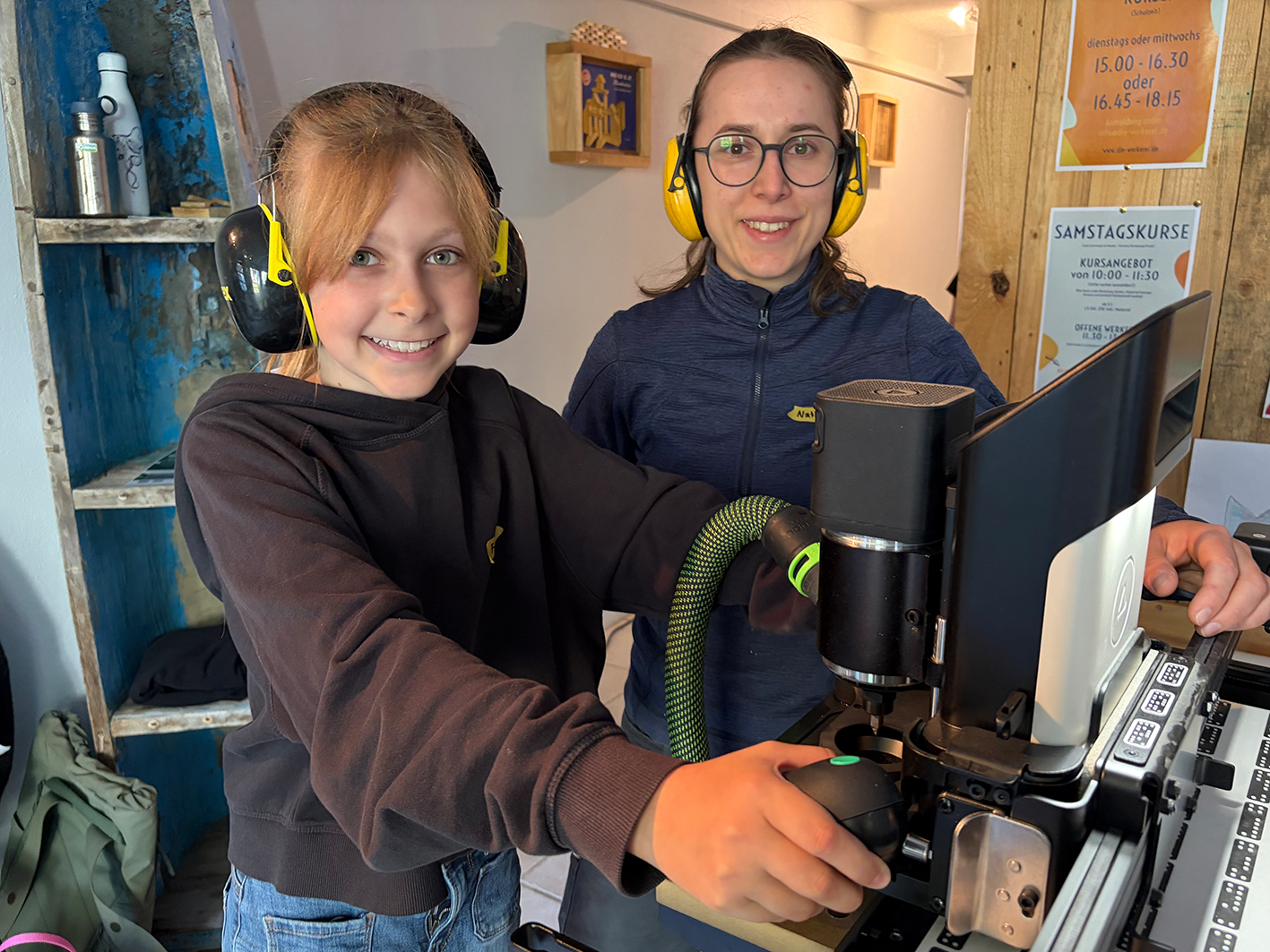 Schülerin arbeitet mit Schreinerin mit einer Fräse.