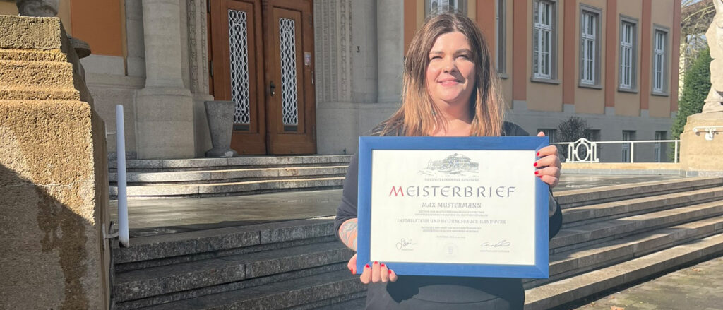 Rebecca Bürgi steht mit gerahmtem Meisterbrief in der Hand vor der Handwerkskammer Konstanz.