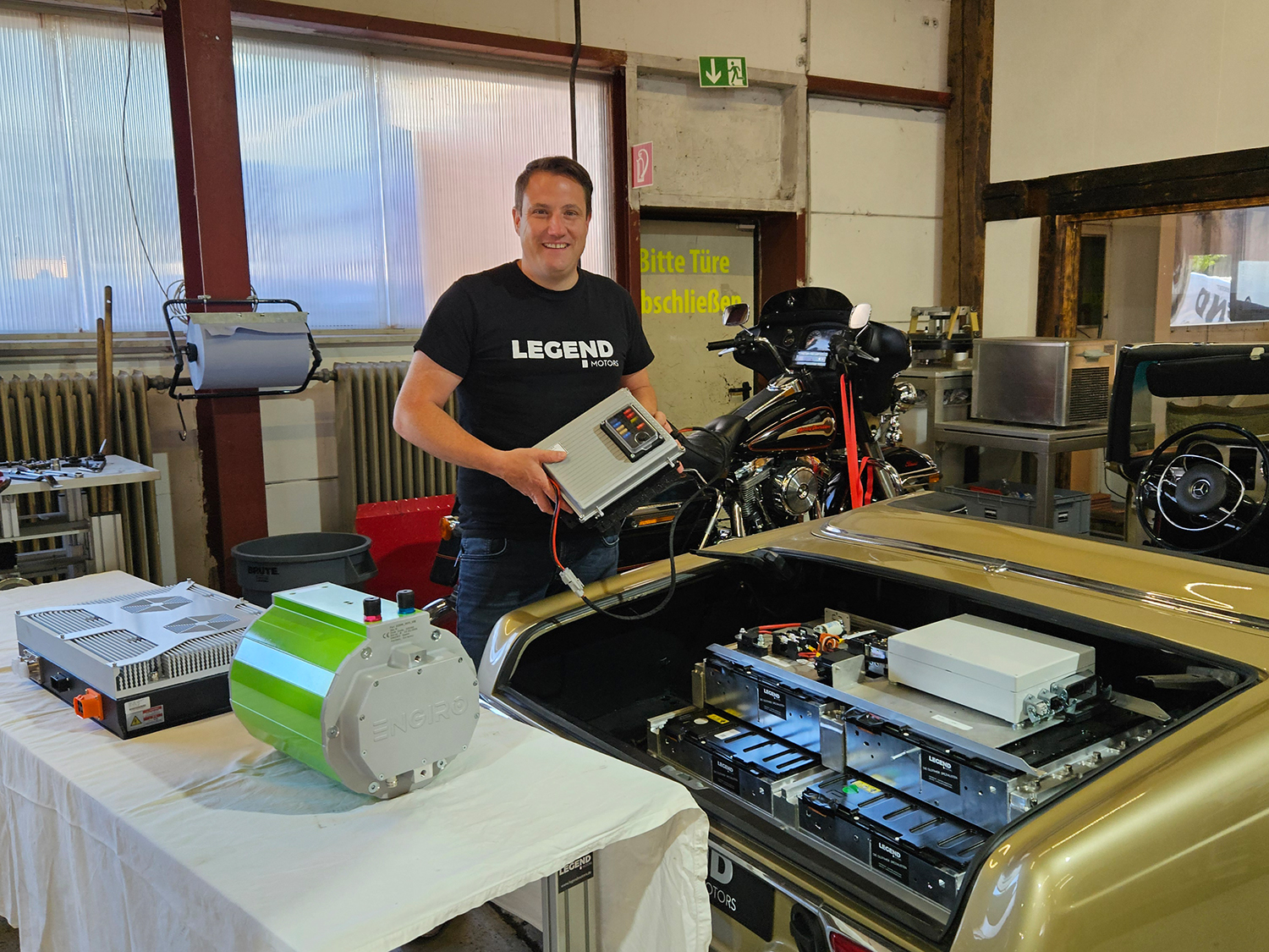 Clemens Hummel vor Motor eines Oldtimers mit elektronischer Steuereinheit in der Hand.