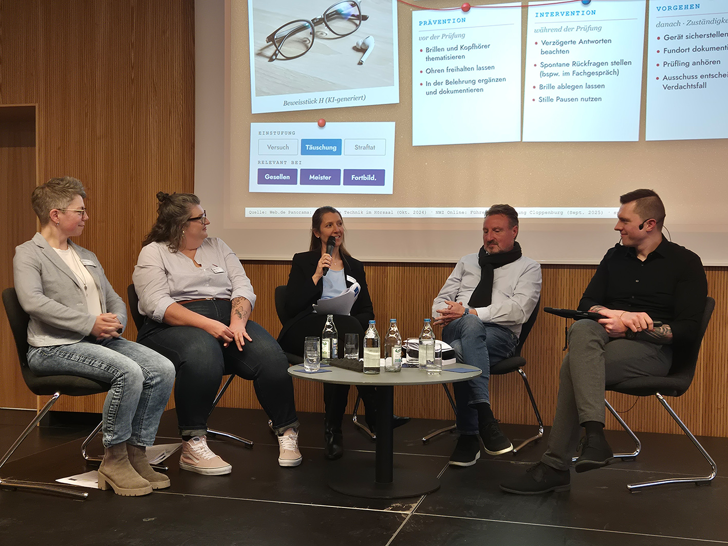 Expertenrunde aus drei Frauen und zwei Männern sitzt auf Podium um einen kleinen runden Tisch. Im Hintergrund sieht man einen Teil einer Power-Point-Präsentation.
