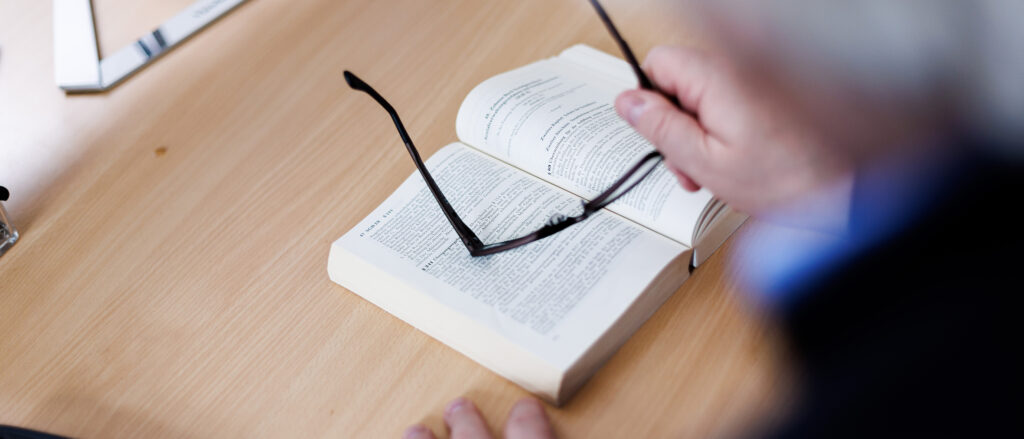 Rechtsberater Joachim Vojta beugt sich sich über ein aufgeschlagenes Buch, Brille in der rechten Hand.
