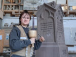 Jaime Bolz mit Werkzeug vor einem alten Grabstein.