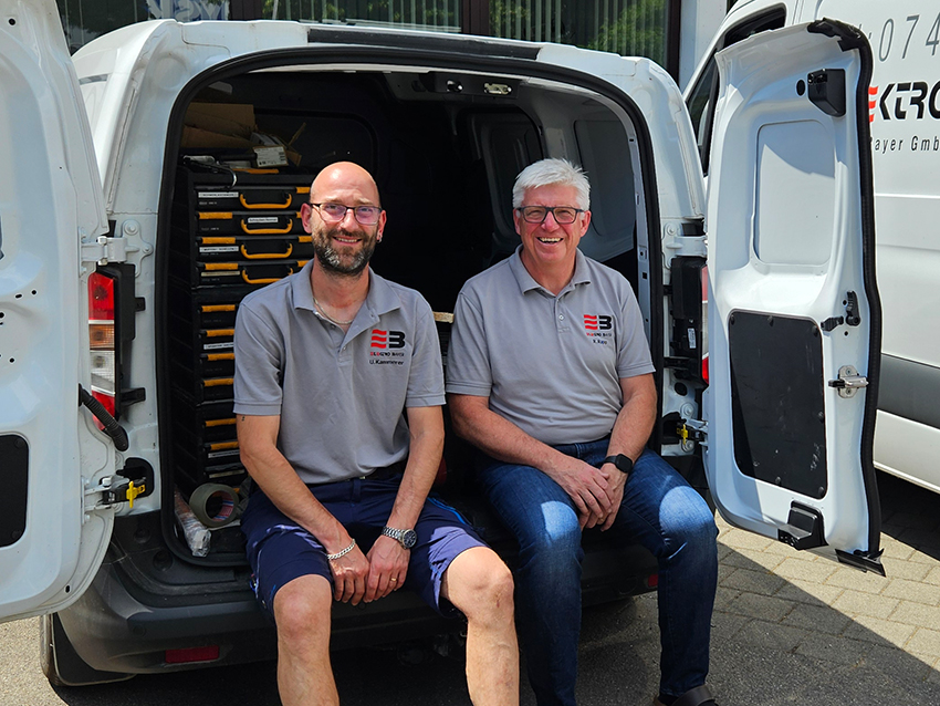 Ulrich Kammerer-Romano und Ralf Rapp sitzen im Firmen-Sprinter mit geöffneten Hintertüren.