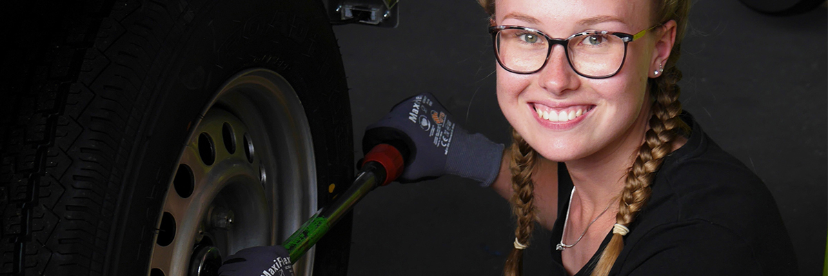 Junge Kfz-Mechatronikerin schraubt an Felge