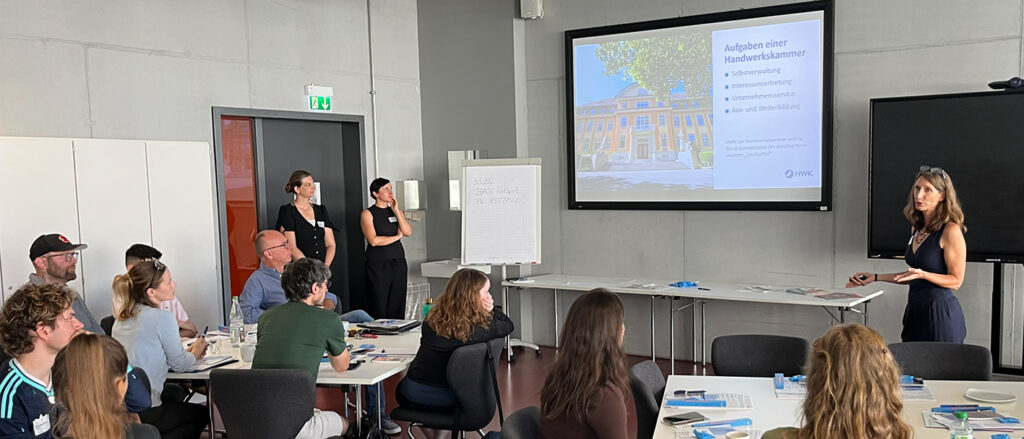 Pressesprecherin Petra Schlitt-Kuhnt erläutert vor einer Power-Point-Präsentation die Aufgaben einer Handwerkskammer