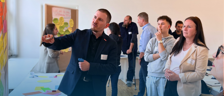 Teilnehmer der Ehrenamtsakademie diskutieren vor einer Stellwand, an der bunte Klebezettel angebracht sind.