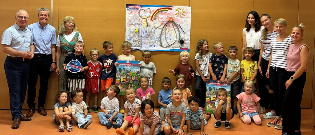 Gruppenfoto vor Siegerplakat mit Erzieherinnen und Handwerkskammer-Präsident Werner Rottler.